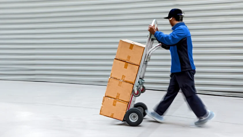 Amazon delivery man rolling packages on a dolley