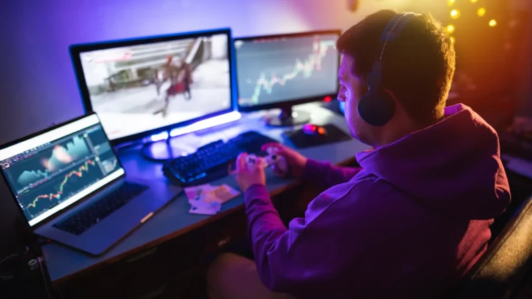 Man sitting at a desk with multiple computer screens, watching financial charts