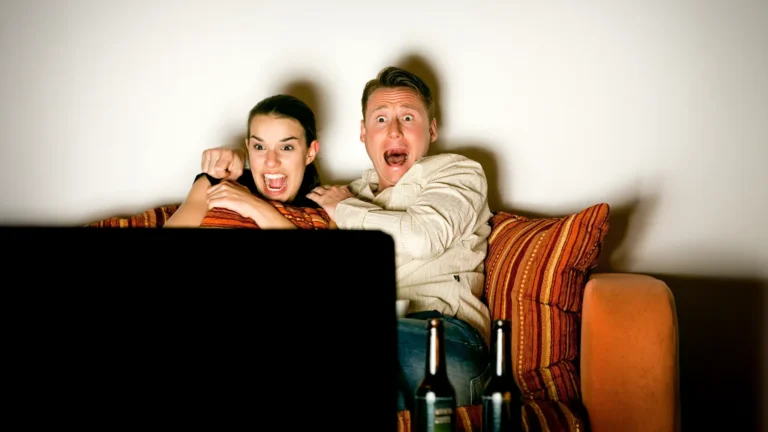 A couple sitting on the couch watching Netflix, with a scared reaction