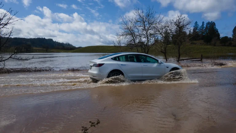 Tesla car driving through a flooded street